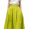 Falda larga plisada de color lima brillante de REVES, con bolsillos laterales y cintura alta. Tejido liso y con caída.