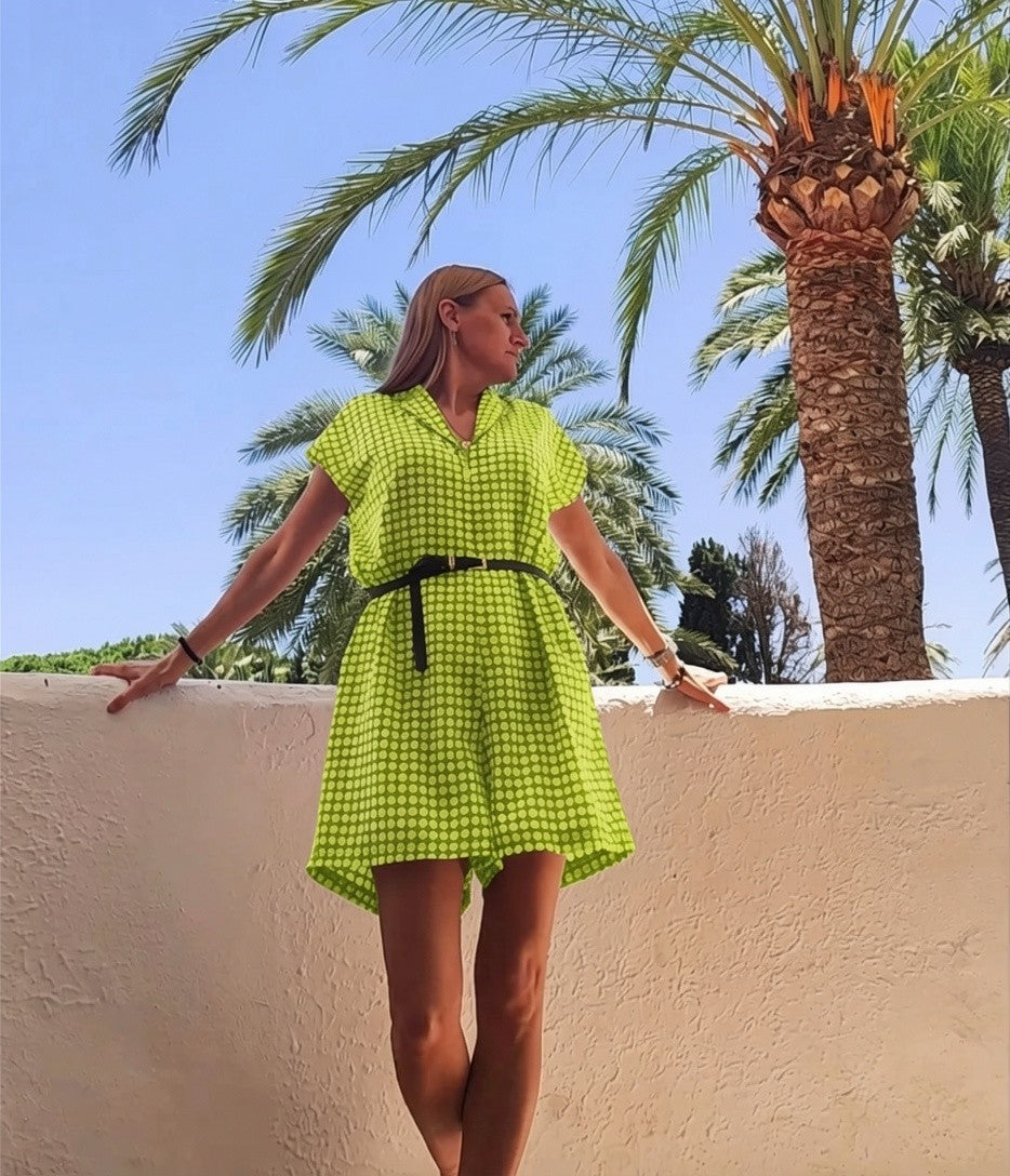Mujer con vestido corto REVES verde lima de estampado geométrico, cuello solapa y cinturón negro en entorno tropical